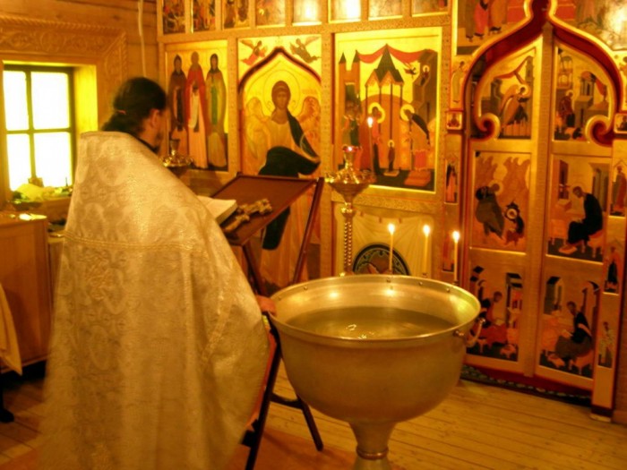 священник читает молитвы перед началом таинства крещения