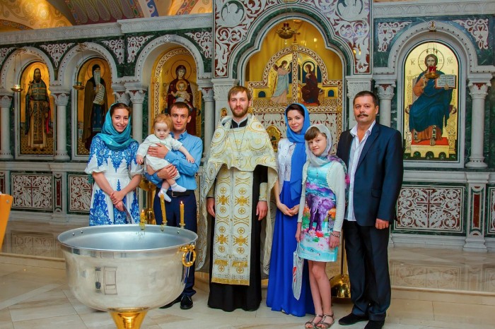 родные и крестные родители с малышом и батюшкой после крещения
