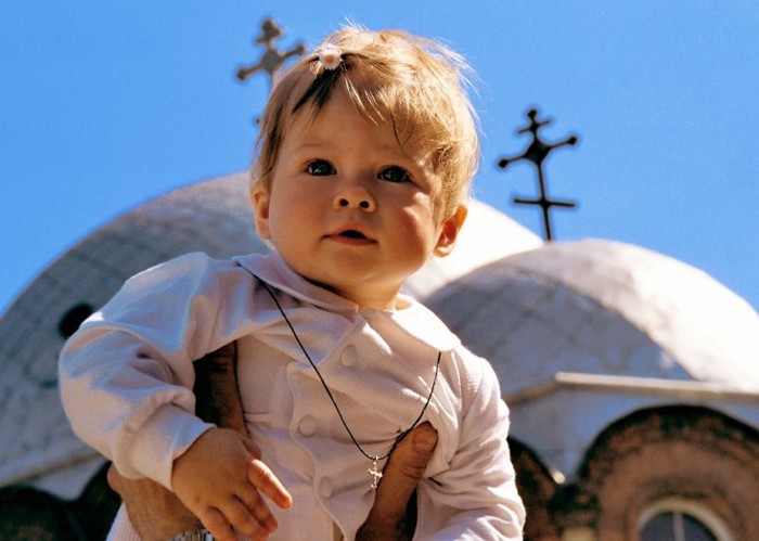 покрещенный малыш на фоне куполов храма и неба