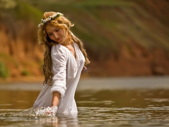 девушка заговаривает воду в реке во время купания в Чистый четверг