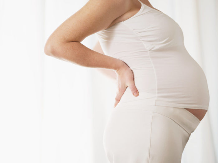 Vista recortada de la mujer embarazada de 7 meses italianos que masajea la espalda. Forma horizontal, vista lateral, espacio de copia.