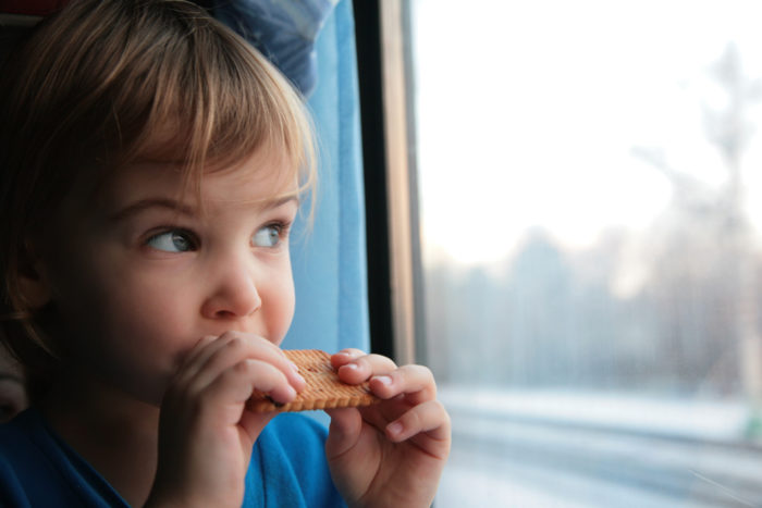 малыш кушает галетное печенье и смотрит в окно поезда