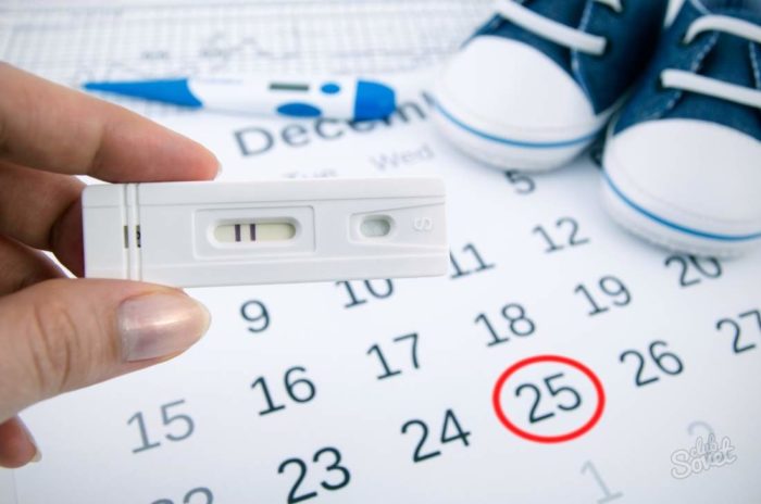 лист календаря и позитивный тест на беременность в руках у девушки
