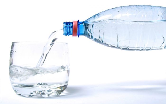 Το μεταλλικό νερό από μια φιάλη χύνεται σε ένα ποτήρι συνταγή για τη θεραπεία βήχα