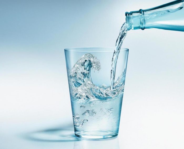 l'acqua minerale da una bottiglia per una persona che soffre di gotta è versata nel vetro