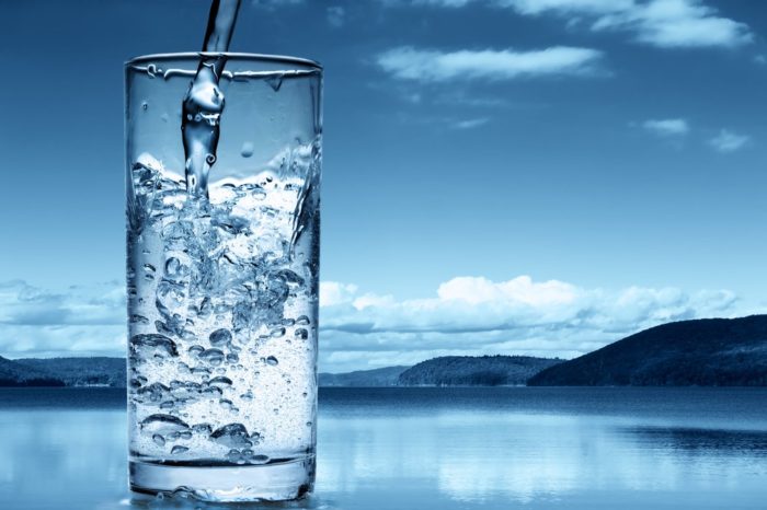 against the background of the lake, mineral water with gas in a glass is poured