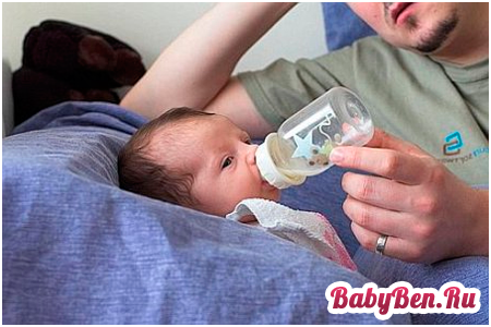 Отец кормит малыша с бутылочки
