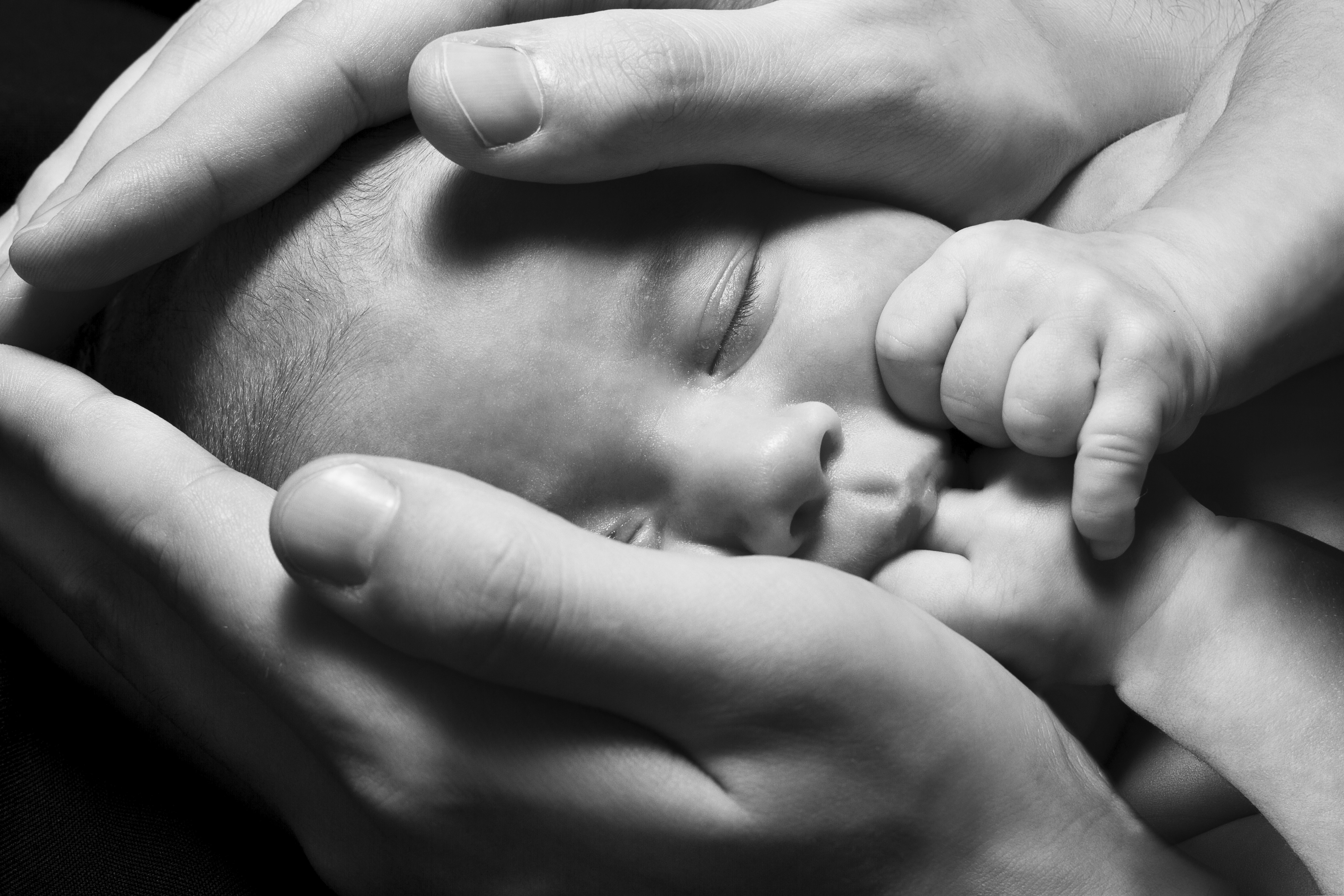 Newborn baby sleeping into parents hands