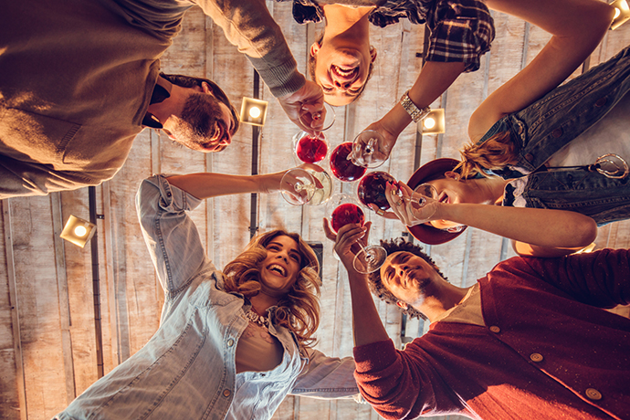 Below view of young happy friends toasting with wine.